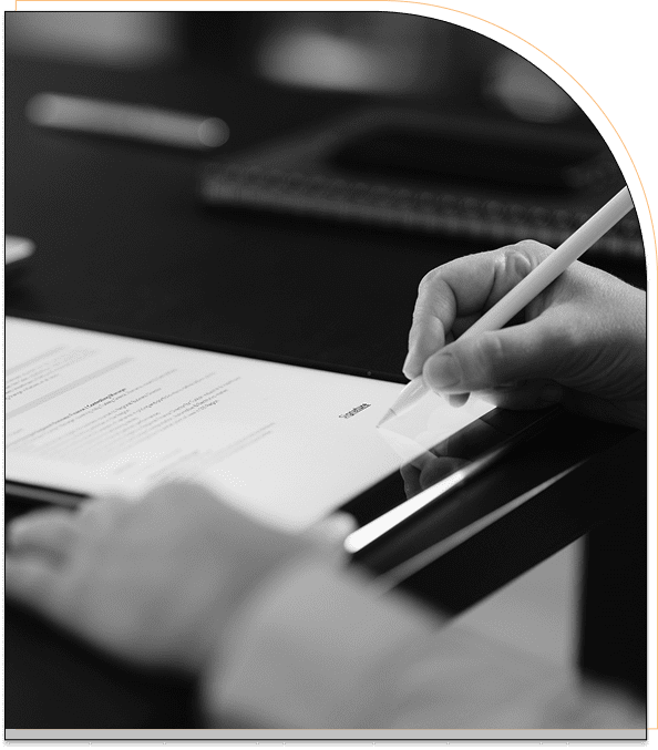 Person writing on paper with a pencil at a desk.